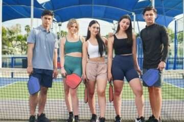 group of boys and girls standing at pickleball coart wearing essential pickleball outfits and apparel