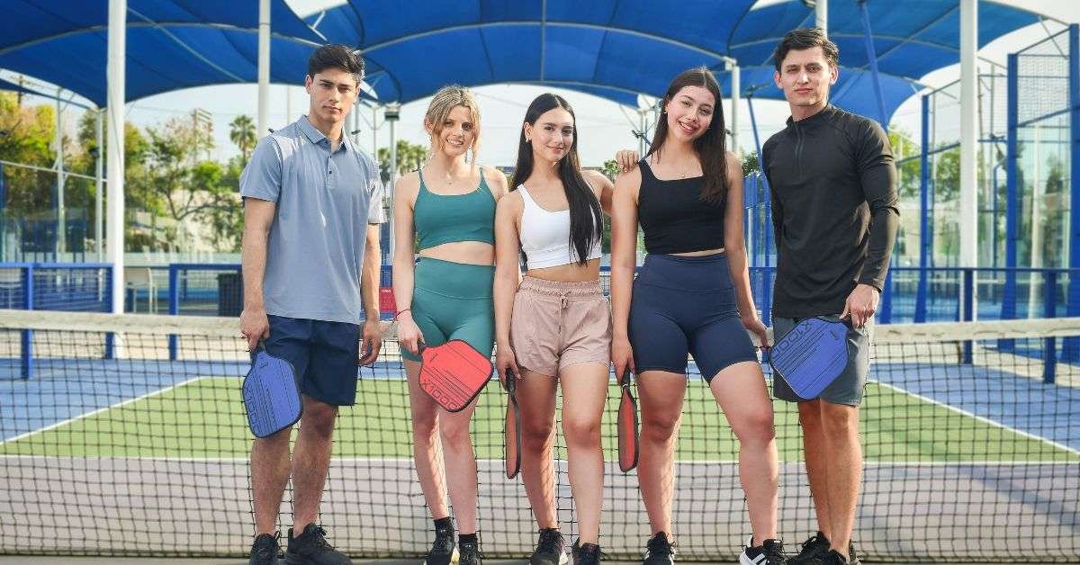 group of boys and girls standing at pickleball coart wearing essential pickleball outfits and apparel
